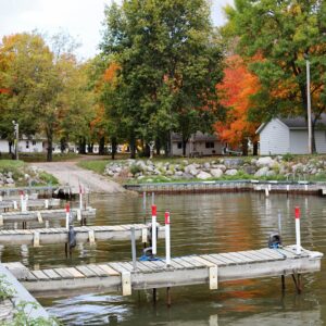 Dock along shore of Mille Lacs Lake with fall foliage in background.