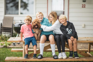 Groups of kids with pet dog smiling at the camera while on vacation.