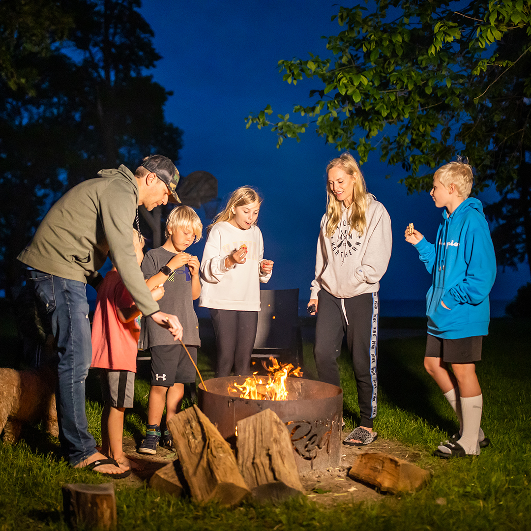 A family roasts smores standing around a bonfire at The Red Door Resort