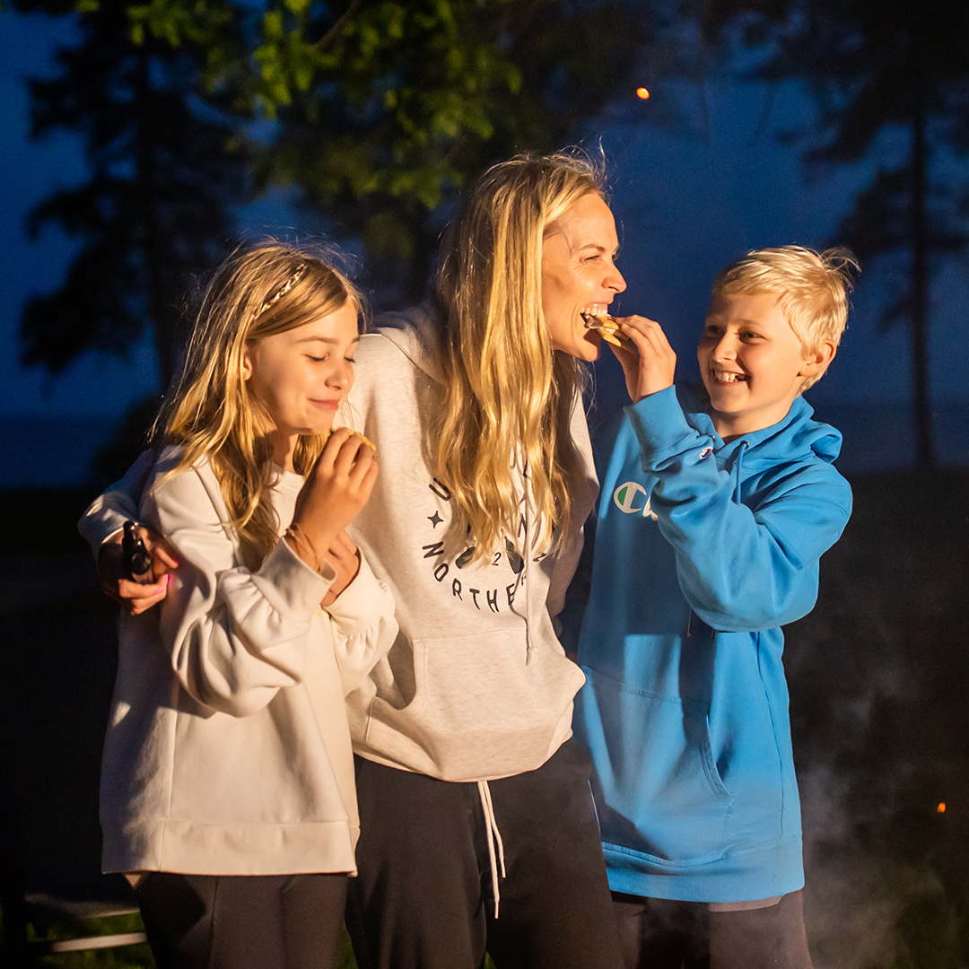 A mom and her kids eat smores around a campfire at The Red Door Resort.