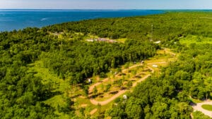 Bird's eye view of seasonal RV site with lake in distance.