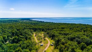 Bird's eye view of seasonal RV site with lake in distance.