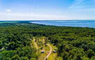 Bird's eye view of seasonal RV site with lake in distance.